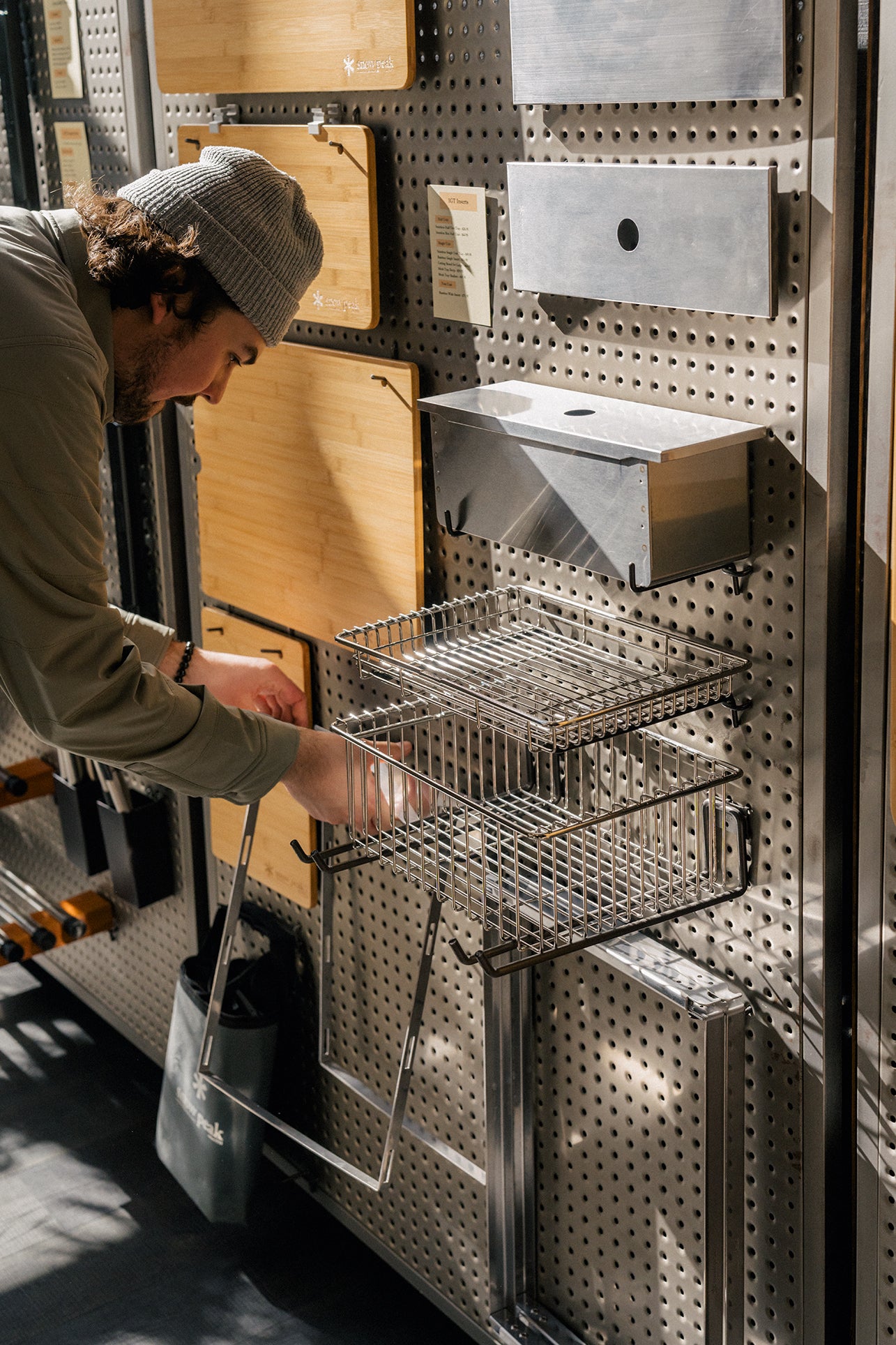 A retail associate at Snow Peak flagship in Portland, Oregon merchandising the Iron Grill Table, an outdoor cooking kitchen setup.