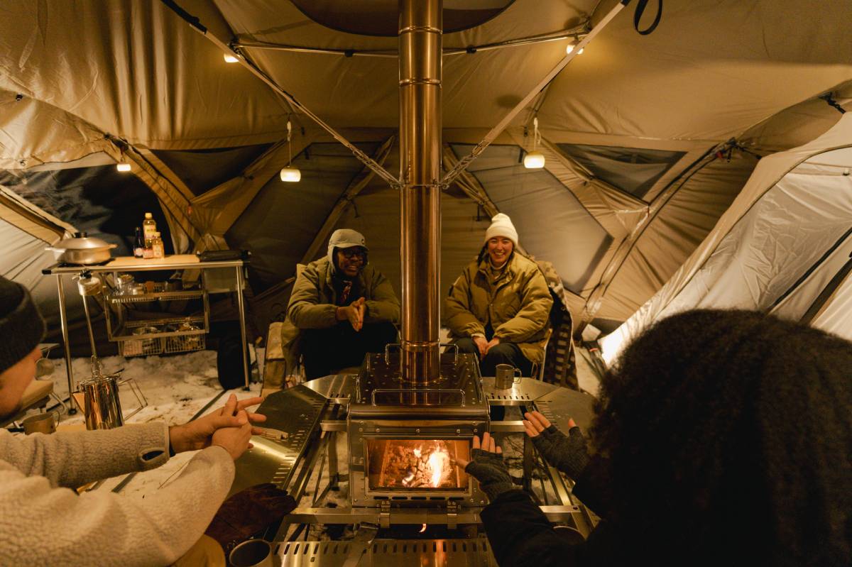 friends gathered around fireplace under tent