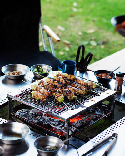 Skewers of meat are cooking on a grill on a table
