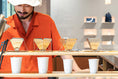 A Snow Peak cafe employee pours hot water over four drip coffee set-ups.