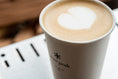 A freshly poured latte in a paper Snow Peak cafe cup.