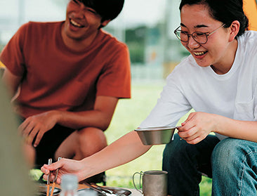 A couple sits on the Camp Couch while enjoying coffee.